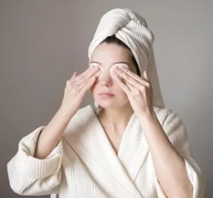 Woman applying warm compresses on eyes